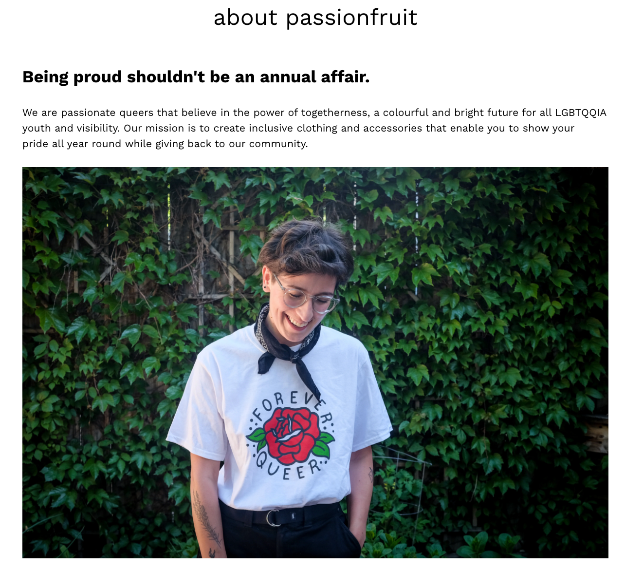Person in ’Forever Queer’ shirt smiling in front of greenery.
