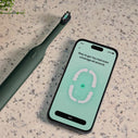 An electric toothbrush sits next to a phone app open to display even tooth brushing coverage.