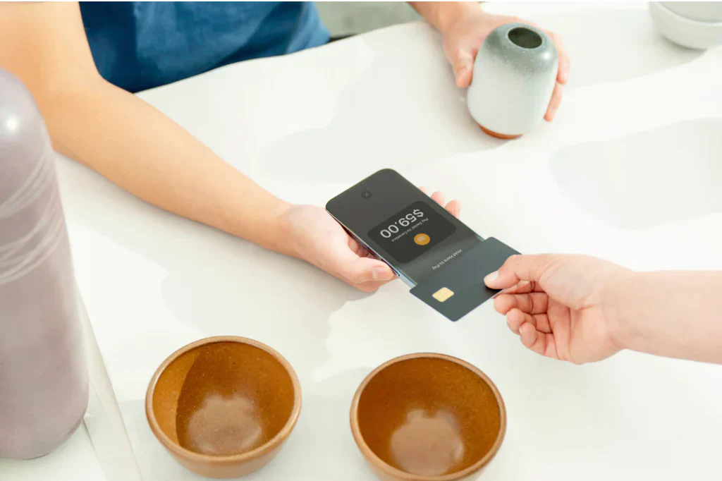 Person tapping their credit card against an iPhone using Tap to Pay technology.
